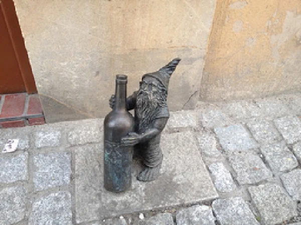 Zwerg mit Weinflasche vor Vinothek