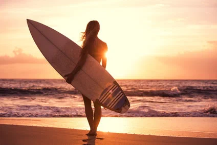 Surferin mit Surfboard am Strand