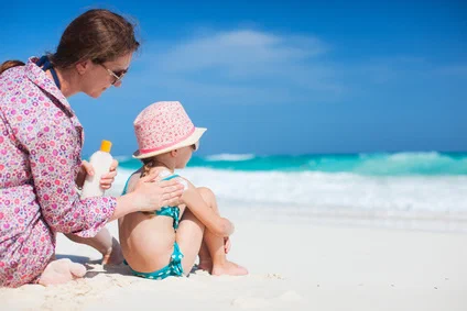 Kind wird mit Sonnencreme eingeschmiert